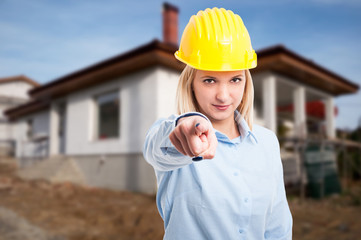 Woman engineer wearing yellow helmet pointing camera