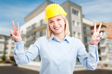 Blonde lady engineer wearing helmet showing peace