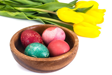 Easter painted eggs and bunch of tulips on a white