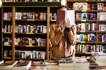Woman Reading at a Bookstore - obrazy, fototapety, plakaty