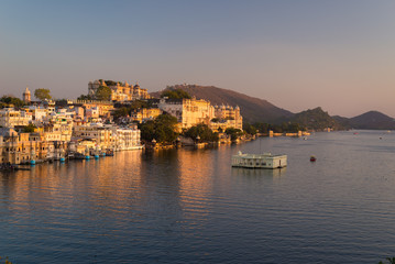 Fototapeta na wymiar The famous city palace on Lake Pichola reflecting sunset light. Udaipur, travel destination and tourist attraction in Rajasthan, India