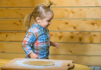 cute child in checkered shirt cooking with dough and flour