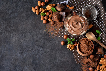 Schwarzer Lebensmittelhintergrund mit Kakao, Nüssen und Schokoladenpaste.