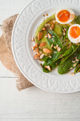 Salad with almond , eggs and spinach on the white wooden table vertical