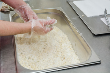 The cook fries meat in a deep fryer.
