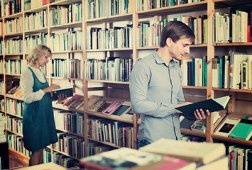 Young smiling man reading book while