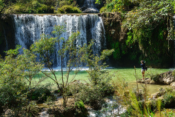 Asian woman taking pictures of The Thi Lo Su or Thee Lor Sue Waterfall  located in the Umphang Wildlife Sanctuary, a UNESCO World Heritage site, Thailand 