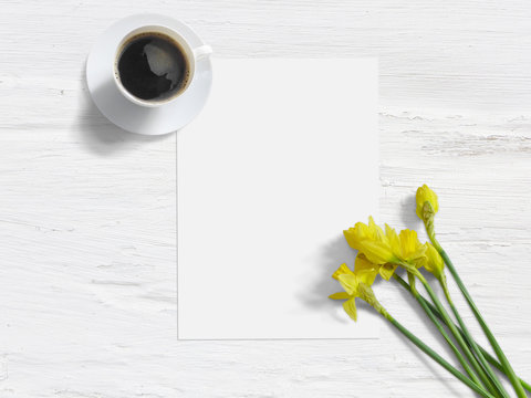 Spring styled stock photo. Feminine mock-up with daffodil flowers, Narcissus, list of paper, and cup of coffee. Shabby white background. Flat lay picture, top view, image for blog or social media.