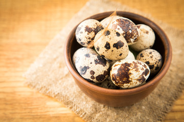 Quail eggs in a bowl on sacking on a wooden surface