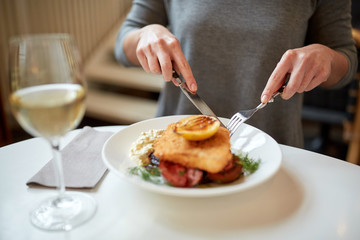 woman eating fish salad at cafe or restaurant