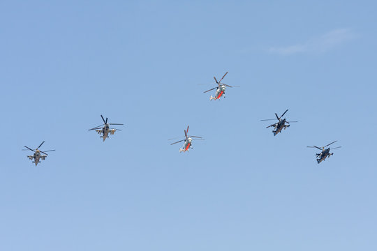 Ka-50 Black Shark (Chornaya Akula, Hokum A) and Ka-52 Alligator (Hokum B) attack helicopters with distinctive coaxial rotor system and Ka-27 Kamov military helicopters fly against blue sky background