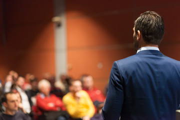 Speaker giving a talk on corporate Business Conference. Audience at the conference hall. Business...