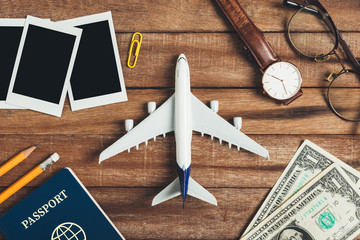 Preparation for Traveling concept, pencil, money, passport, airplane, watch, eyeglasses, photo frame on a vintage wooden background with copy space.