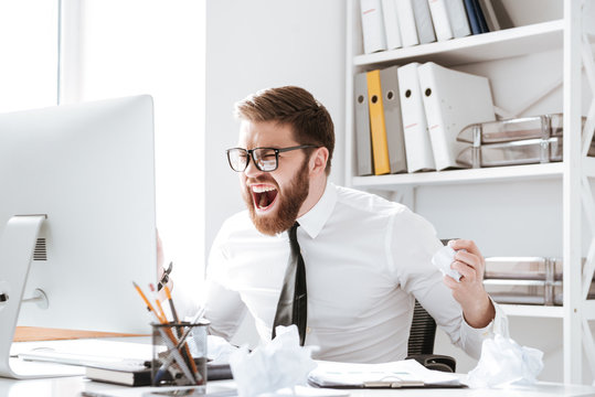 Screaming angry businessman holding documents.