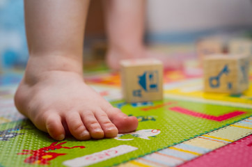 Children's leg standing on the Developing rug with children's cubes
