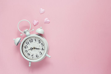Background with white alarm clock and hearts on pink. Place for