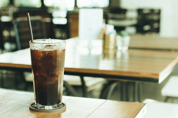 Cold black coffee on the table in the coffee shop with vintage f