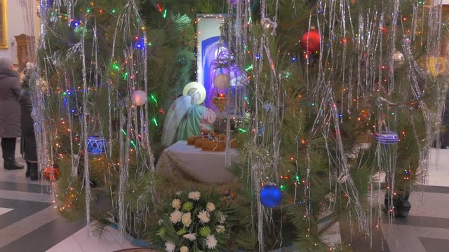 an Old Saint Mary Icon With Two Angels, a Lot of Glass Baubles and Toys, Under a Decorated Fir Tree in an Orthodox Christian Cathedral With Impressive Decor