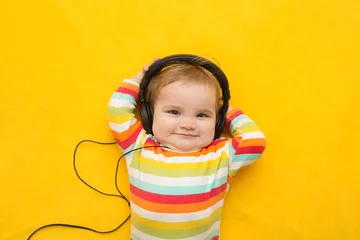 Fototapeten the baby with headphones on a yellow background © ulza