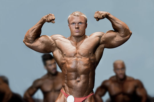 Athlete's double bicep pose. Bodybuilder flexing biceps on stage. Posing in front of competitors. Challenge is accepted.