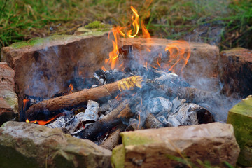 Campfire burning in day light. Equipped place for bonfire