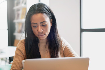 A beauty blogger is using modern smartphone and a portable computer for the work while sitting in a cafe. International student girl is studying online by a laptop connected to a wifi network.