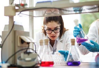 Two dedicated female lab scientists meticulously work together, focusing on chemical research and...