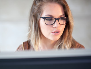 Beautiful young woman sitting at her desk working on a computer.