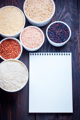 Several types of rice on the table with culinary notebook, top view