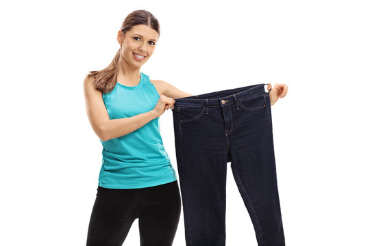 Cheerful woman holding a pair of oversized jeans