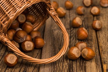 Hazelnuts in a basket on old wooden table.