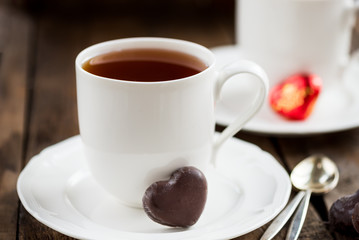 Hot Tea or Chocolate in White Cups with Chocolate Hearts and Lit Candles on Wooden Rustic Background, Valentines Day Concept