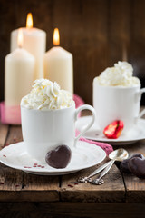 Hot Tea or Chocolate in White Cups with Chocolate Hearts and Lit Candles on Wooden Rustic Background, Valentines Day Concept