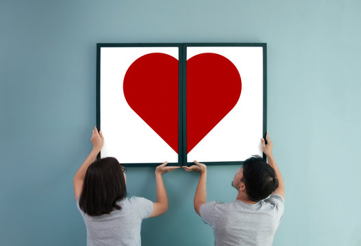 Asian couple holding heat in picture frames.