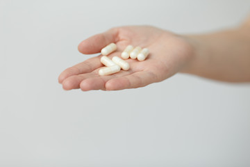 Hand is giving capsules on white background.