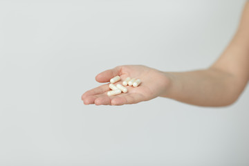 Hand is giving capsules on white background.
