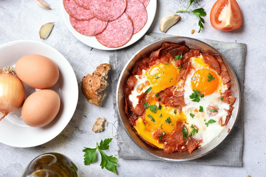 Fried eggs with salami, bacon and tomatoes