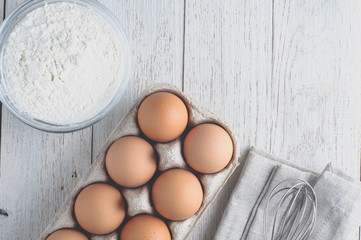 Eggs and ingredients for baking on a light wooden table. Top vie
