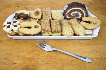 Sweet cakes on a plate wooden background. Cookies, gingerbread, dry sweet cakes with chocolate icing. Christmas and Easter.
