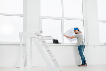 White interior for renovation and repair with ladder, windows and foreman or builder looking at...
