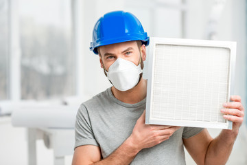 Worker holding air filter for installing in the house ventilation system. Purity of the air concept