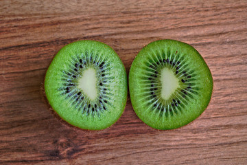 Fototapeta na wymiar Closeup of two kiwi halves on a wooden table