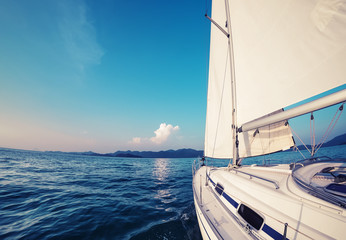Obraz premium Sailing vessel moves in a sea under the sails towards the island