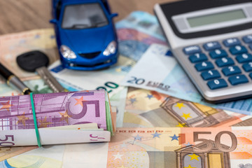 blue toy car with euro banknotes, calculator and pen.