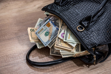 black woman handbag full of money, on desk. © RomanR
