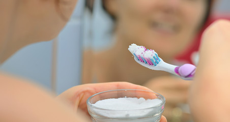 Woman brightening teeth with  bicarbonate