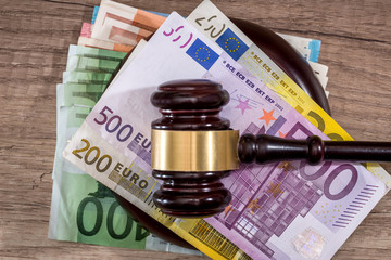 Judge hammer and different euro banknotes on desk.