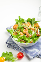 Shrimp salad with cherry tomatoes in bowl on striped napkin. White background