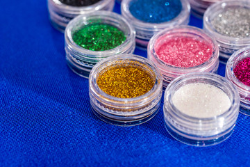 many round jars with  multi-colored bright glitter for nail polish.
