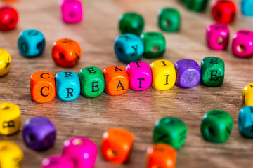 Word "creative" of the colored wooden cubes on wooden desk.